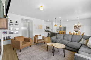 Living room featuring light wood finished floors, recessed lighting, baseboards, and an inviting chandelier