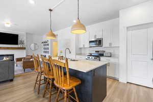 Kitchen featuring stainless steel appliances, a breakfast bar, a sink, light countertops, and light wood finished floors