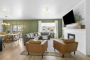 Living room with plenty of natural light, a glass covered fireplace, a decorative wall, and light wood-style flooring