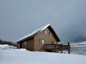 Snow covered back of property featuring a deck