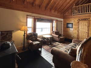 Living area with lofted ceiling, wood ceiling, wooden walls, and wood finished floors