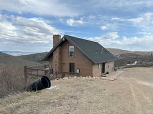 Rear view of house featuring a chimney, a deck with mountain view, and cooling unit