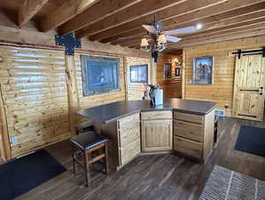 Bar featuring dark wood-style floors, beam ceiling, visible vents, a barn door, and a ceiling fan