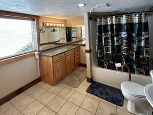 Full bath featuring visible vents, a textured ceiling, toilet, and shower / bath combo with shower curtain