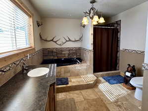 Full bath with a shower with shower curtain, a textured ceiling, toilet, and an inviting chandelier