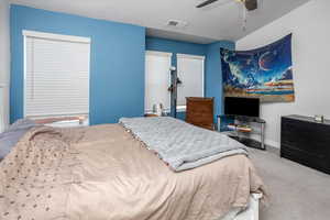 Carpeted bedroom with ceiling fan, visible vents, and baseboards