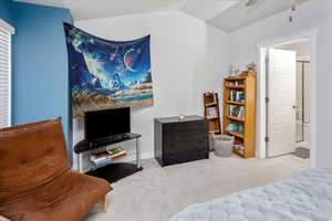 Carpeted bedroom with lofted ceiling and ceiling fan