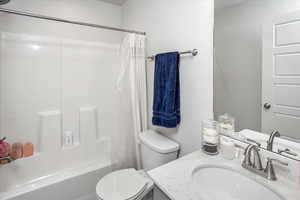 Bathroom featuring shower / bath combination with curtain, vanity, and toilet