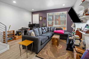 Living area featuring light wood-type flooring, stairway, and recessed lighting