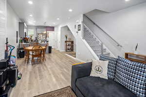 Living area featuring light wood-type flooring, stairway, baseboards, and recessed lighting