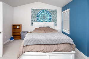 Carpeted bedroom featuring baseboards and vaulted ceiling