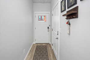 Doorway with light wood-style flooring and baseboards