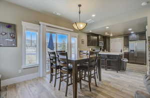 Dining area featuring visible vents, light wood-style flooring, and baseboards