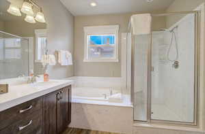 Bathroom with a stall shower, a garden tub, and vanity