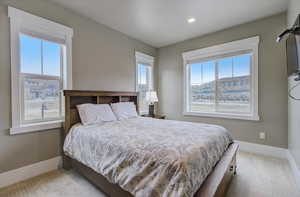 Carpeted bedroom with recessed lighting, multiple windows, and baseboards