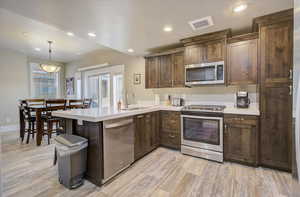 Kitchen featuring stainless steel appliances, light countertops, visible vents, a sink, and a peninsula