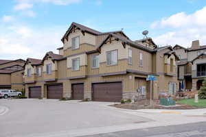 Townhome / multi-family property featuring a garage, a residential view, stone siding, and board and batten siding