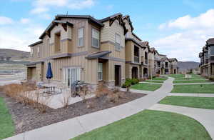 Exterior space featuring stone siding, a patio, board and batten siding, and a front yard