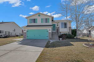 Tri-level home with driveway, a garage, fence, a front yard, and brick siding