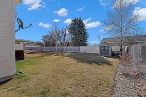 View of yard with a big shed, a fenced backyard, and a shed