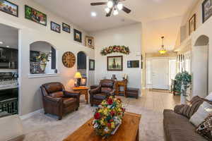 Living area with light carpet, light tile patterned floors, a towering ceiling, and baseboards