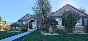 View of front of home featuring stucco siding, stone siding, and a front lawn
