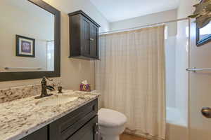 Bathroom featuring toilet, tile patterned flooring, vanity, and shower / tub combo with curtain
