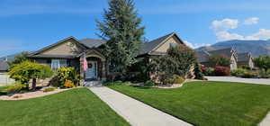 View of front facade featuring a front yard, a mountain view, driveway, and stucco siding