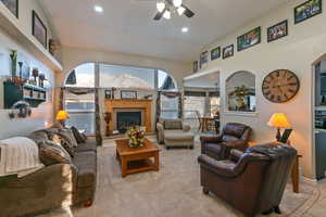 Living area with recessed lighting, a ceiling fan, a glass covered fireplace, light carpet, and vaulted ceiling