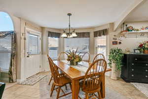 Dining room with light tile patterned floors, plenty of natural light, and a chandelier