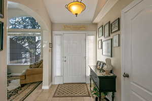 Entryway with light tile patterned floors, arched walkways, and baseboards