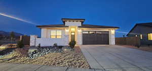 Prairie-style house with a garage, concrete driveway, stone siding, and stucco siding