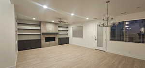 Unfurnished living room featuring baseboards, visible vents, a ceiling fan, a tile fireplace, and wood finished floors