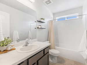 Bathroom featuring visible vents, toilet, shower / bath combo with shower curtain, vanity, and tile patterned floors