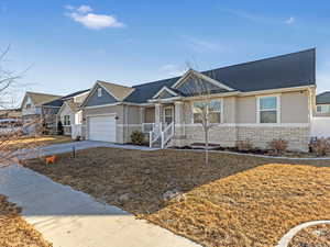 Ranch-style home with a garage, a shingled roof, stone siding, concrete driveway, and stucco siding
