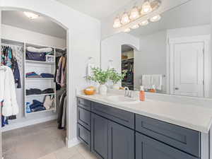 Bathroom with tile patterned flooring, a spacious closet, baseboards, and vanity