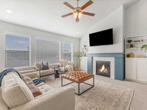 Carpeted living room featuring ceiling fan, recessed lighting, built in features, vaulted ceiling, and a glass covered fireplace