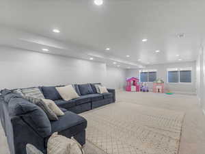 Carpeted living room with recessed lighting, visible vents, and baseboards