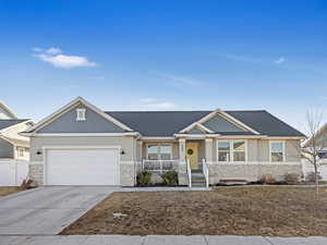 Craftsman-style house featuring driveway, stone siding, a porch, and stucco siding