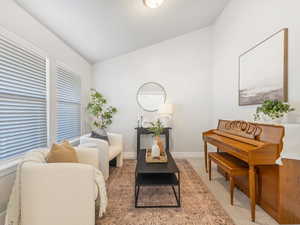 Living area featuring lofted ceiling, light carpet, and baseboards