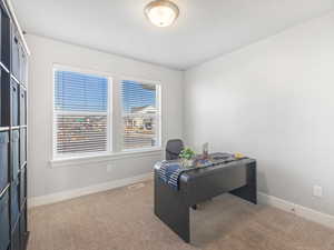 Office area with carpet, visible vents, and baseboards