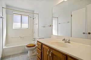 Full bathroom featuring toilet, vanity, a textured ceiling, and bathing tub / shower combination