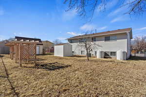 Back of property featuring central air condition unit, fence, a storage unit, and an outdoor structure