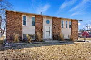 Raised ranch with a front yard, brick siding, and fence