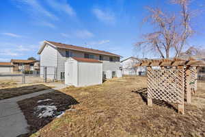 Back of property featuring a gate, an outdoor structure, fence, and a shed