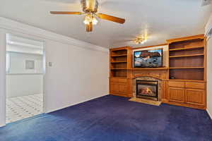 Unfurnished living room featuring electric panel, visible vents, baseboards, a fireplace, and dark carpet