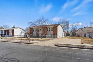 View of front facade featuring driveway, a fenced front yard, and brick siding