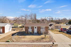 View of front of house featuring brick siding, fence, driveway, and a mountain view