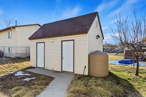 View of outbuilding with fence and an outbuilding