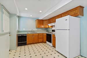 Kitchen with white appliances, brown cabinets, light countertops, under cabinet range hood, and a sink